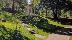 Ein Pavillon mit goldener Kuppel, einer Steinmauer und einer Treppe, die dorthin führt.
