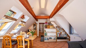 Ein Essbereich mit Holztisch und -stühlen, einem Bücherregal und Blick durch Dachfenster.