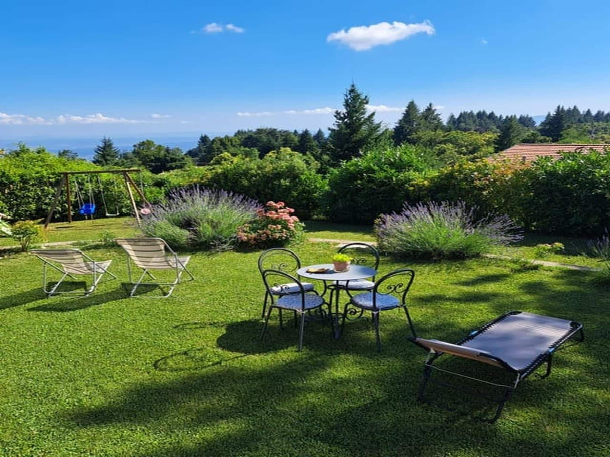 A well-maintained garden with a swing set, a table with chairs, and a lawn.