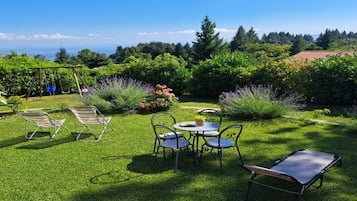 A well-maintained garden with a swing set, a table with chairs, and a lawn.