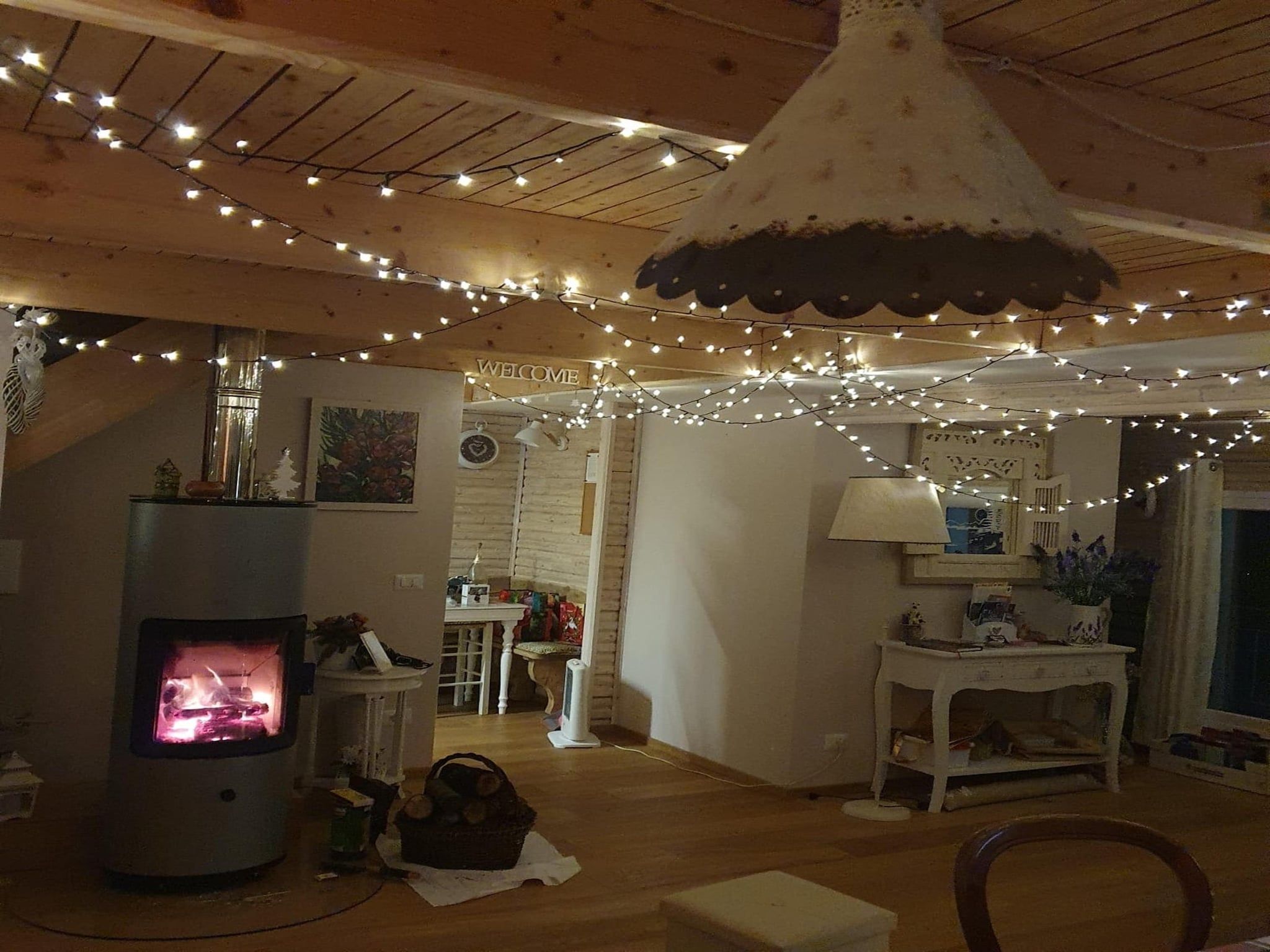 A cozy room with a fireplace, wooden beams, and string lights.