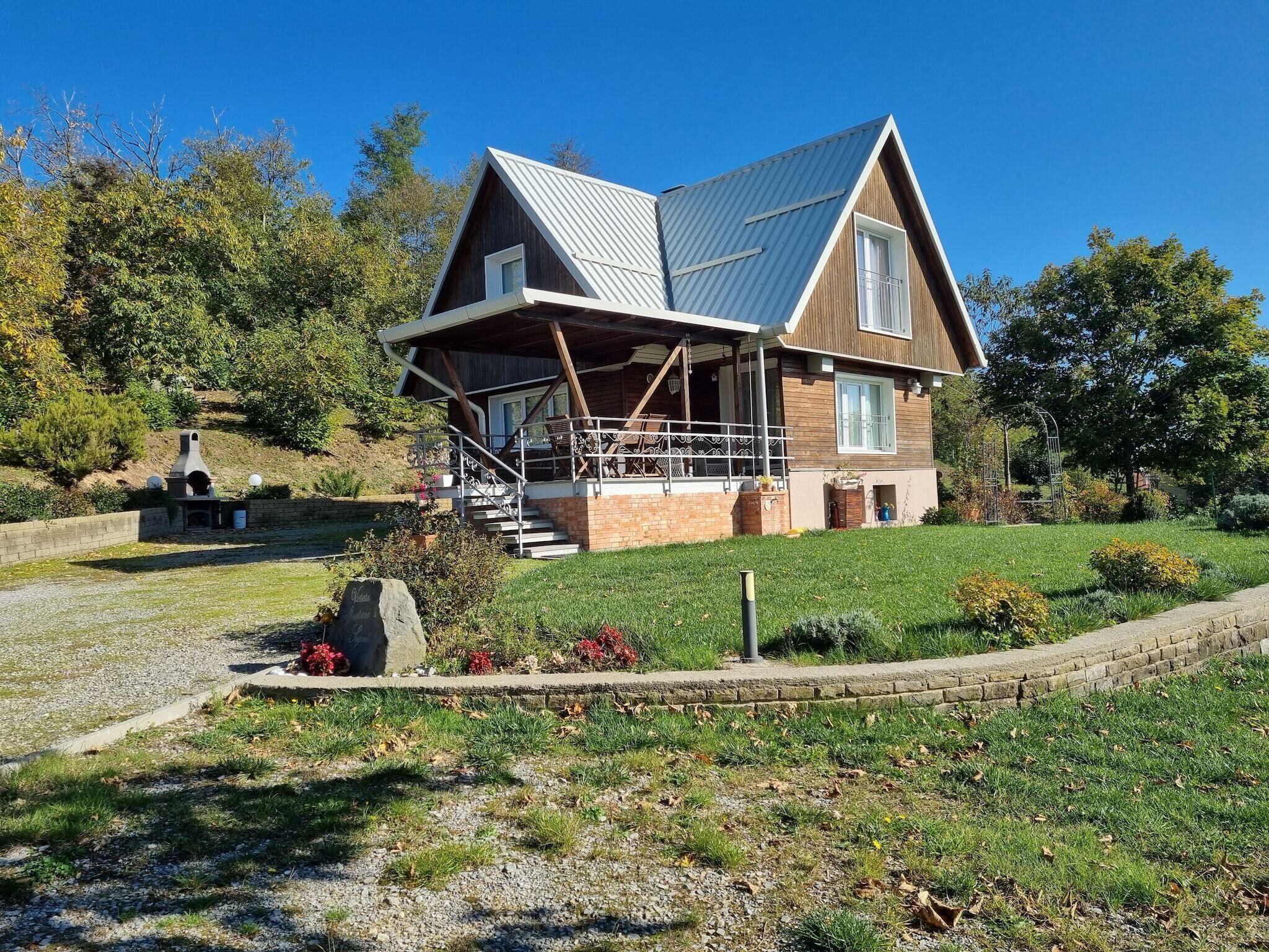 A two-story house with a metal roof, a covered porch, and a stone pathway leading to the entrance.