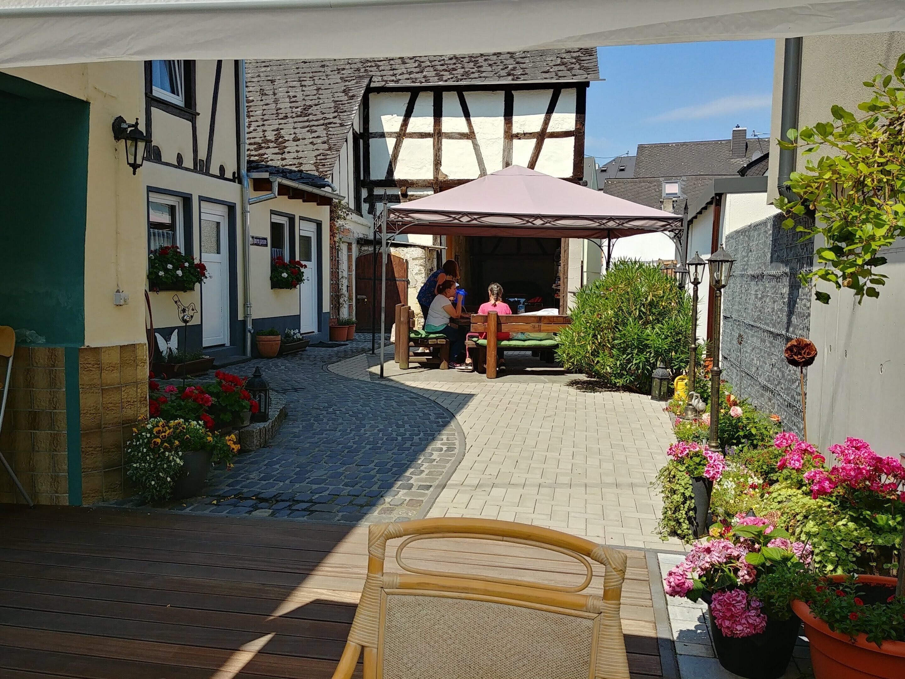 Ein Innenhof mit einer hölzernen Bank, Topfpflanzen und einem Gebäude mit Satteldach.