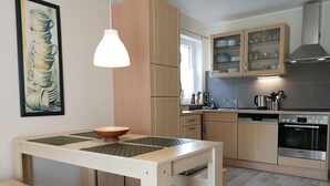 Una cocina moderna con armarios de madera, un horno Bosch y un comedor con mesa y banco.