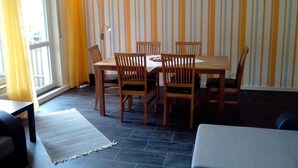 Un comedor con una mesa y sillas, una lámpara, un tapete y una ventana con cortinas.