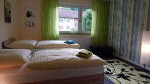 Un dormitorio con dos camas, una ventana con cortinas, un radiador y una alfombra estampada.