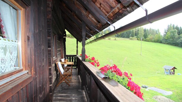 Une cabane en bois avec une véranda, une table et des chaises.