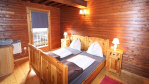 Une chambre rustique en bois, avec un lit, deux lampes de chevet, un radiateur et une fenêtre.