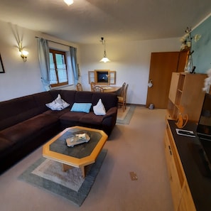A living room with a sofa, a coffee table, a dining table with chairs, and a cabinet. - Apartment 'Leni' with Balcony and Wi-Fi (Sonthofen)