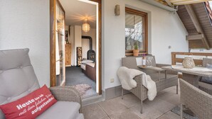 A cozy outdoor seating area with wicker furniture, a small table, and a red pillow with text. - Holiday Apartment 'Omatina' with Balcony and Wi-Fi (Bannewitz)