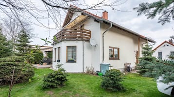 Ein Haus mit Satteldach, einer Satellitenschüssel und einem kleinen Garten mit geschnittenen Büschen.