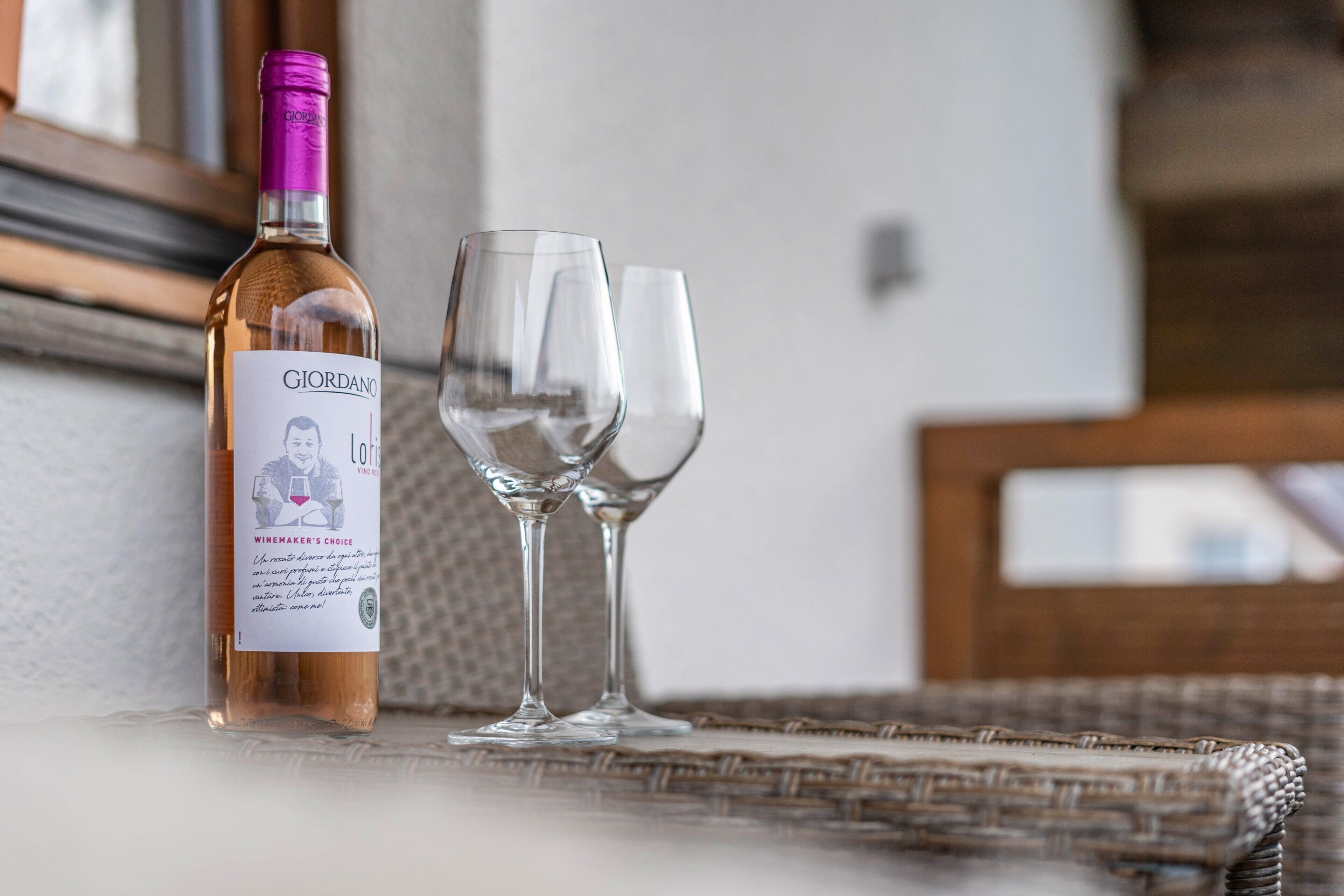 Une bouteille de vin et deux verres posés sur une surface en osier.