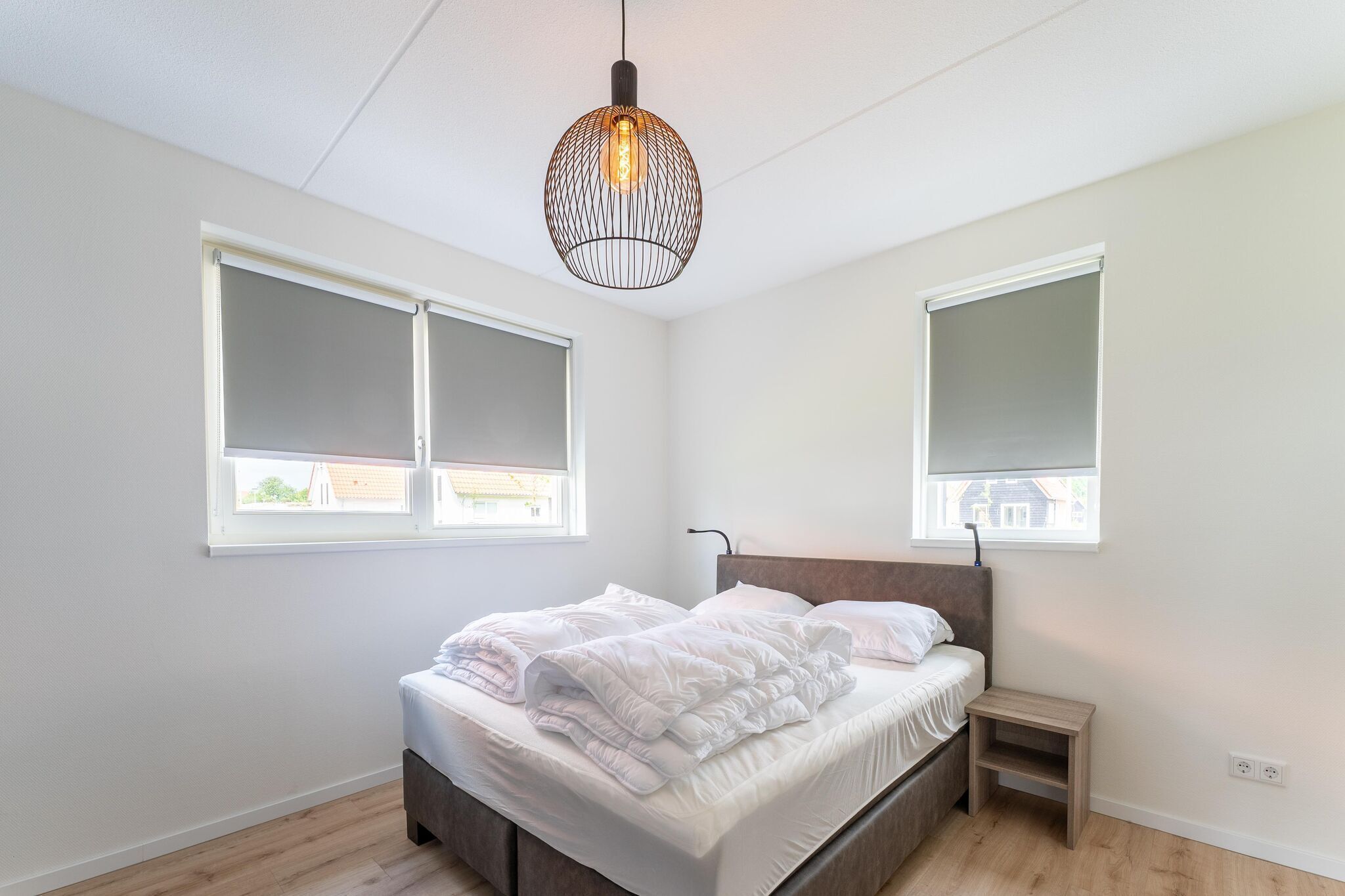 Ein Schlafzimmer mit Bett, Nachttisch und Pendelleuchte.