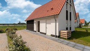 Een modern gelijkvloers huis met een rode dakbedekking, witte gevels en een oprit van grind.