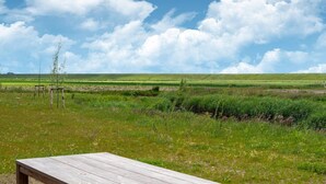 Een houten bankje in een grasveld met een heldere lucht en een verre horizon.