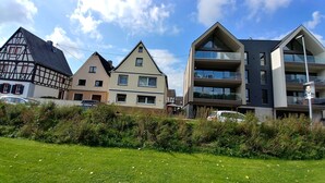 Een rij huizen met verschillende bouwstijlen, waaronder een traditioneel vakwerkhuis, een modern tweegezinshuis en een eigentijds appartementencomplex.