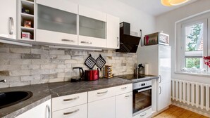 Uma cozinha moderna com armários brancos, bancada preta, forno embutido e janela com vista.