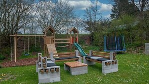 En legeplads med en trærutchebane, gynger og en lille klatrestruktur.