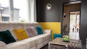En moderne stue med en beige sofa, farverige puder, et træsofabord og et stort spejl p å væggen.