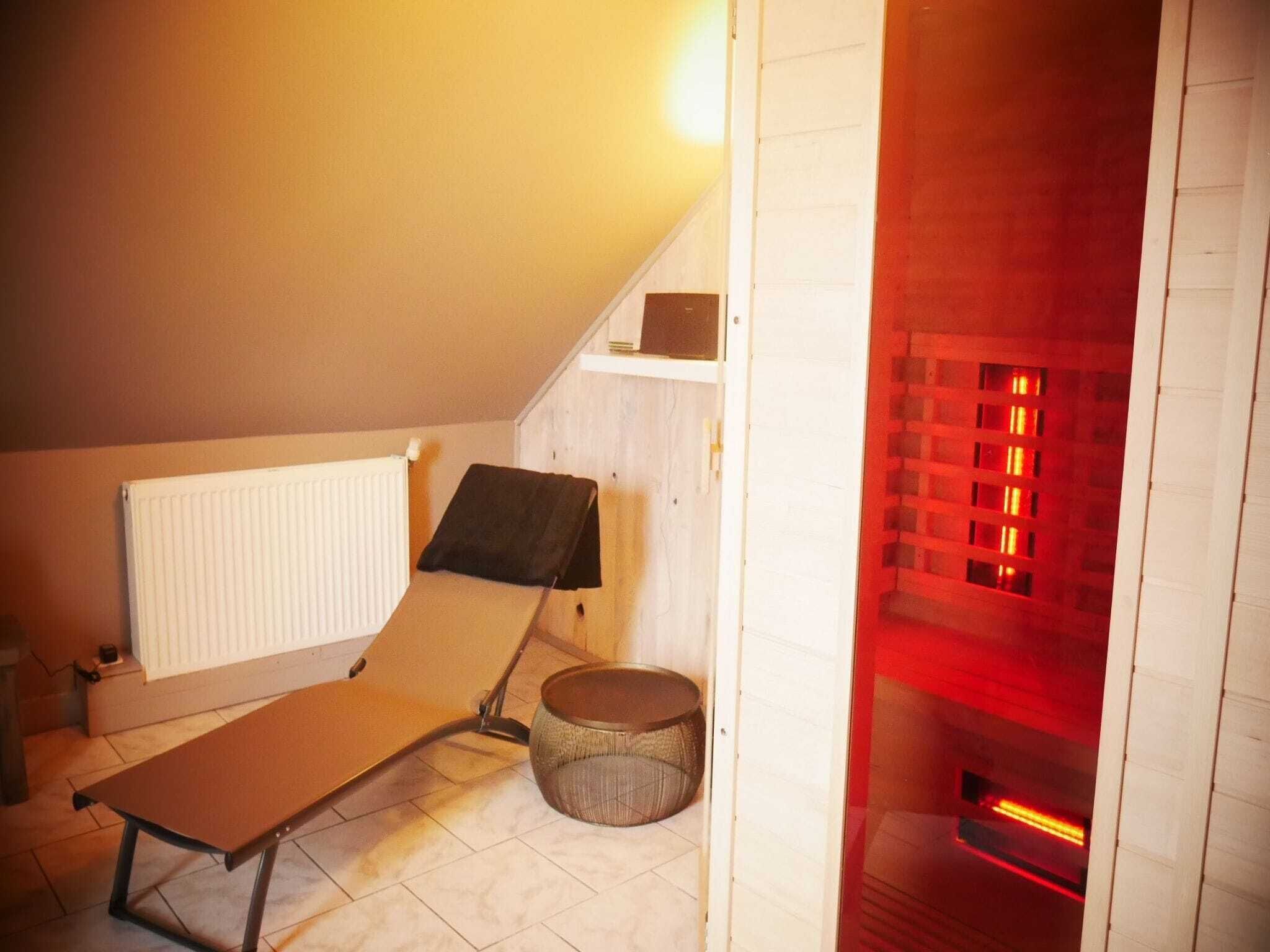 A small, cozy room with a sloped ceiling, a radiator, a bench, a basket, and a red-lit fireplace.