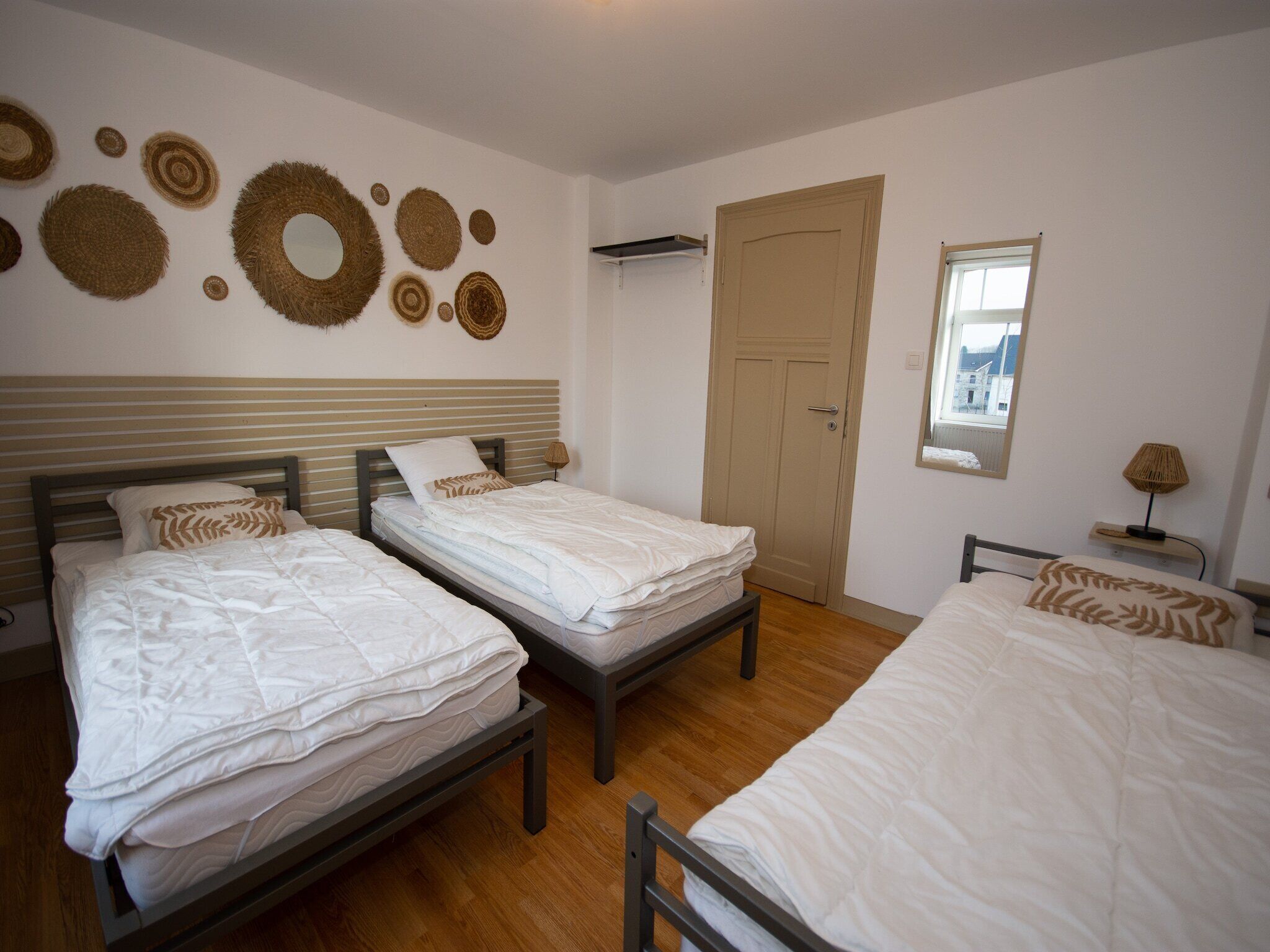 Une pièce avec trois lits, un plancher en bois et une porte.