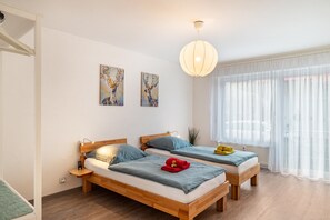 Une pièce avec deux lits en bois, un luminaire suspendu et deux tableaux accrochés au mur.