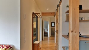 Een hal met houten vloer, een spiegel, een houten kast en een schuifdeur naar een badkamer.