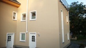 A two-story building with a beige exterior, white doors, and windows.