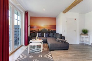 A modern living room with a gray sofa, a white coffee table, and a large mural of a sunset over a pier.