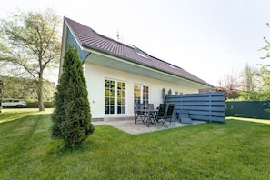 A modern house with a sloped roof, large windows, and a patio area with outdoor furniture.