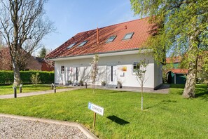 Un bâtiment avec un toit recouvert de tuiles rouges, une façade blanche et un panneau indiquant un parking d’été.
