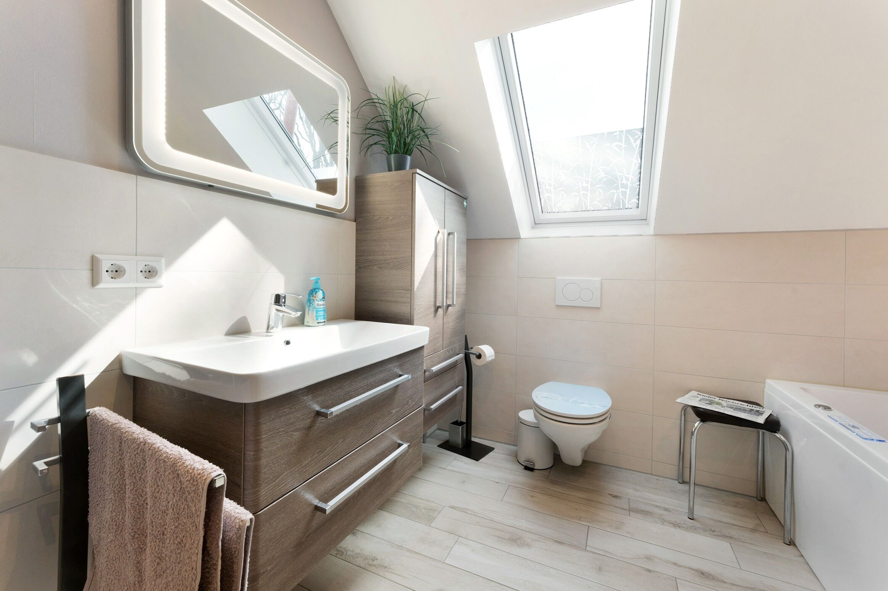 A modern bathroom with a vanity, toilet, and bathtub.
