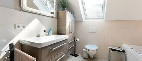 A modern bathroom with a vanity, toilet, and bathtub.