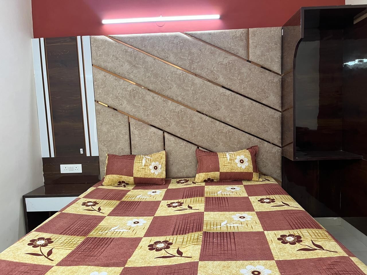 A modern bedroom with a checkered bedspread, two pillows, and a headboard with a geometric design.