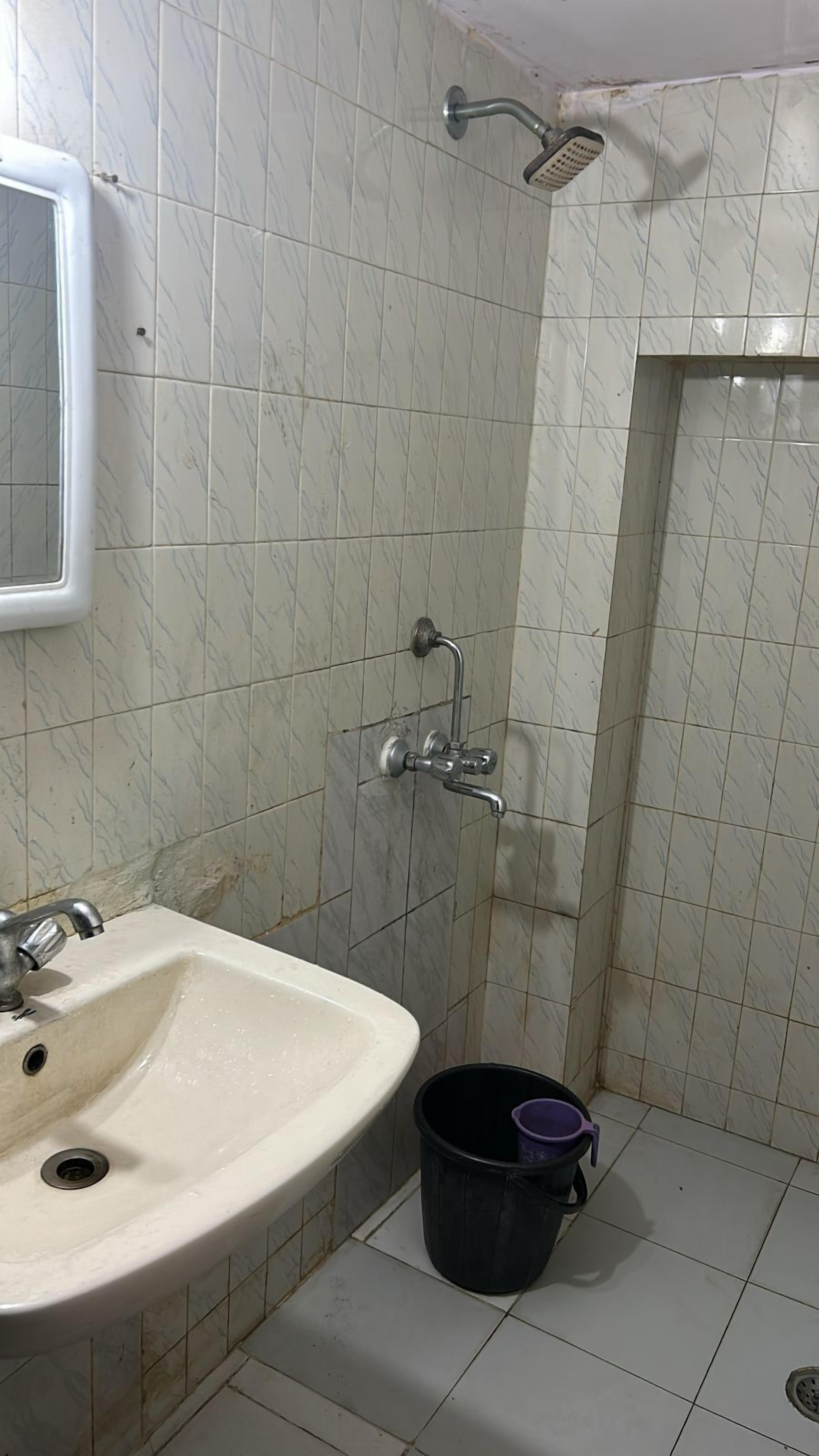 A bathroom with a sink, a shower, and a mirror.