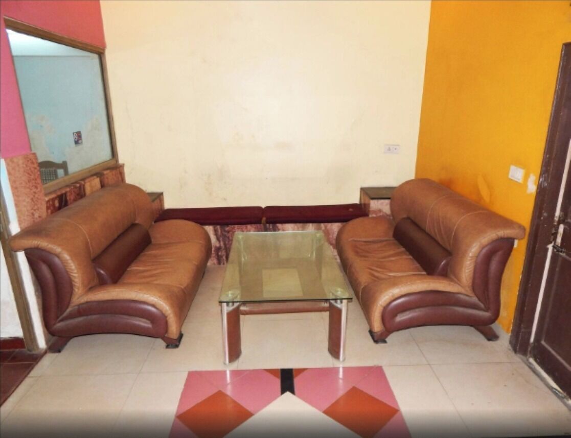 A living room with two leather sofas, a glass coffee table, and a patterned rug.