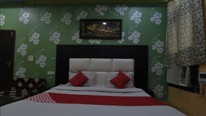 Ein Zimmer mit einem Bett, einem gerahmten Bild an der Wand und einem gemusterten Vorhang.