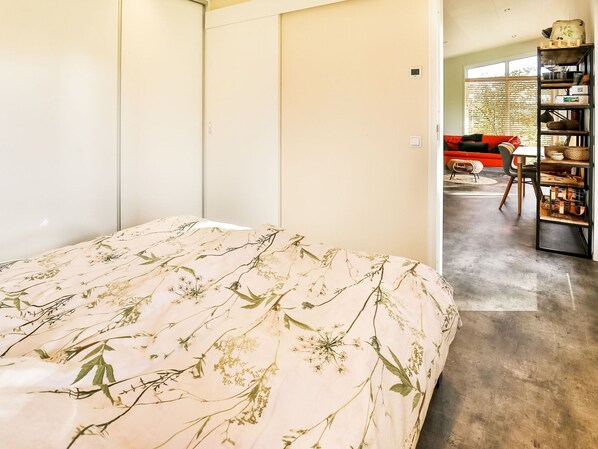 A bedroom with a bed, a wardrobe, a red sofa, and a bookshelf. - Holiday Home in Tripscompagnie near Nature (Tripscompagnie)