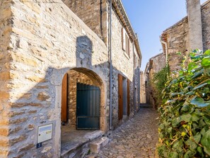 A narrow cobblestone street flanked by stone buildings with arched doorways and wooden shutters. - Vineyards & Village Stay (Minerve)