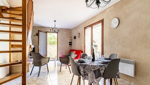 A dining area with a table set for four, a red sofa, and a staircase leading to an outdoor area.