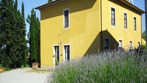 A yellow building with a symmetrical facade, a central entrance, and a chimney.