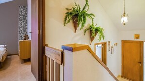A staircase with a wooden handrail and a stone accent wall.