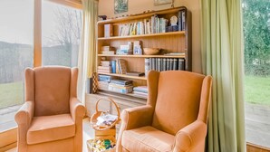 A cozy living room with two armchairs, a bookshelf, and a view of the outdoors.