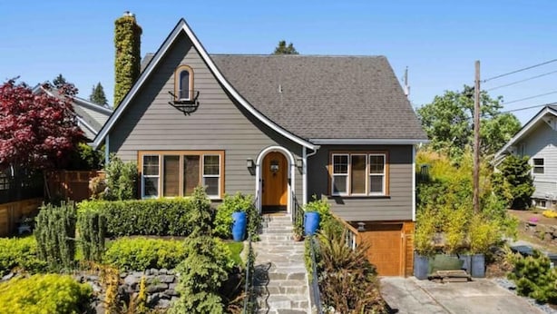 A two-story house with a stone pathway leading to the front door, surrounded by well-maintained gardens and a wooden fence. - Cozy family home minutes from The University of Puget Sound! (Tacoma)
