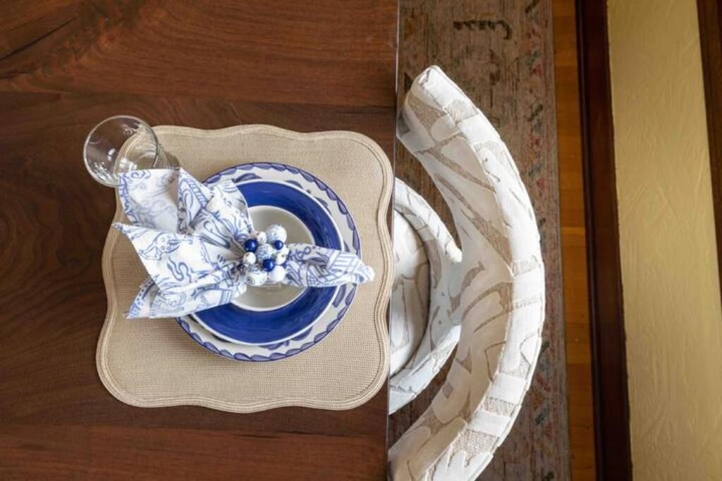 A dining table with a blue and white plate, a glass, and a folded napkin.