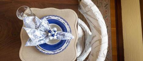 A dining table with a blue and white plate, a glass, and a folded napkin.