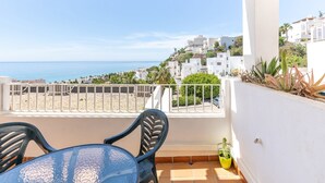 Ein Balkon mit Meerblick, weißen Gebäuden und einem Tisch mit Stühlen.