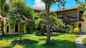 A building with a tiled roof, surrounded by a well-maintained garden with various trees and shrubs. - Fazenda Eco Jardim (Una)