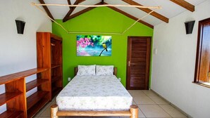 A bedroom with a bed, wooden shelves, a green wall, and a painting of a bird. - Fazenda Eco Jardim (Una)