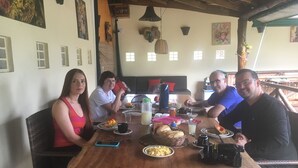 A group of people dining at a wooden table with various dishes and drinks. - Fazenda Eco Jardim (Una)